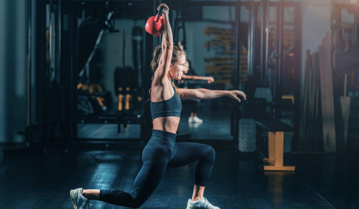Exercise techniques featuring swing style kettlebell and press workout in a modern gym setting